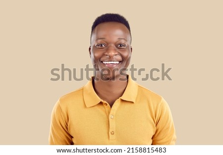 Studio portrait of happy African American man. Cheerful joyful handsome young guy in polo shirt standing on beige background, looking at camera and smiling Foto stock © 