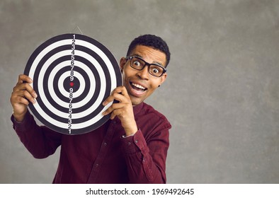 Studio Portrait Of Happy Excited Black Man Holding Shooting Target, Smiling And Looking At Camera. Concept Of Setting Business Objective, Striking Target Audience, Reaching Goal And Achieving Success