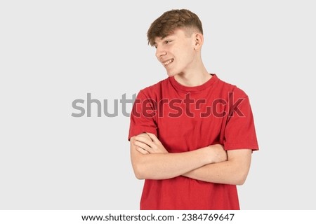 A studio portrait of a happy fifteen year old teenage boy with folded arms