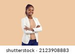 Studio portrait of happy successful confident black business woman. Beautiful young lady in white jacket smiling at camera standing isolated on blank solid beige colour copyspace background