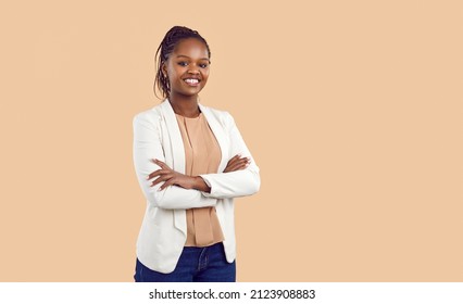Studio portrait of happy successful confident black business woman. Beautiful young lady in white jacket smiling at camera standing isolated on blank solid beige colour copyspace background - Powered by Shutterstock