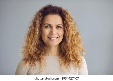 Studio Portrait Of Happy Woman With Long Wavy Golden Brown Hair, Perfect White Smile And Friendly Positive Open Face Expression Looking At Camera. Testimonial Head Shot Of Satisfied Customer Or Client