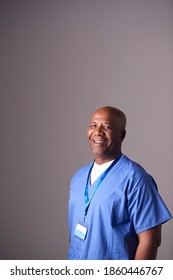 Studio Portrait Of Male Nurse Wearing Scrubs Standing Against Grey Background