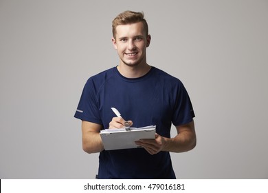 Studio Portrait Of Male Sports Coach With Clipboard