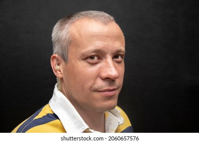 Studio Portrait Of A Man 40-45 Years Old In A Yellow T-shirt On A Dark Background. Perhaps He Is Just A Buyer, An Actor Or A Truck Driver, A Loader Or A Military Pensioner.