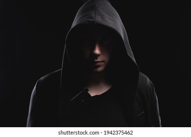 Studio portrait of a man in a hood, a shadow hides his face. Anonymity shadow economy and evasion from the law - Shutterstock ID 1942375462