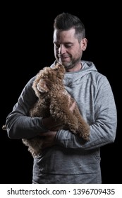 Studio Portrait Of A Man Looking At A Small Red Toy Poodle Dog. Isolated On Black Background. Vertical.