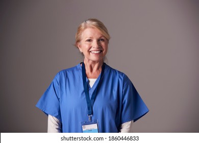 Studio Portrait Of Mature Female Nurse Wearing Scrubs Standing Against Grey Background