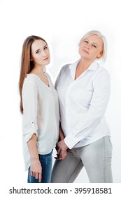 Studio portrait of mother and adult daughter. Peaceful, holding hands in a white shirt on a white background. Isolated. - Shutterstock ID 395918581