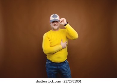 Studio portrait of a plump middle-aged overweight man in bright clothes on a brown background. Nice friendly fat man