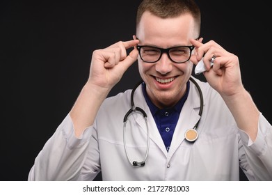 Studio Portrait Of A Positive Laughing Young Doctor In A White Coat Laughing Expressively On A Black Background