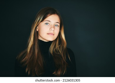 Studio portrait of pretty young teenage girl posing on black background