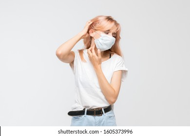 Studio Portrait Of Sad Young Girl In White T-shirt With Medical Mask Who Scratching Itchy Throat. Dry Skin, Irritation, Sensitive Skin, Allergy Symptoms, Dermatitis, Insect Bites. Healthcare Concept.