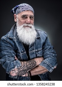 studio portrait of a senior hipster with tattooed arms, wearing a bandana and a long white beard