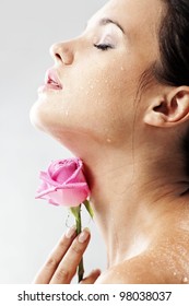 Studio Portrait Of Sensual Beautiful Woman With Rose And Water Droplets On Her Face