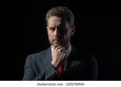 Studio Portrait Of Serious Businessman Wearing Suit And Tie And Looking Thoughtfully While Standing At Isolated Dark Background. Copy Space. Mature Business Man Thinking, Closeup Face.