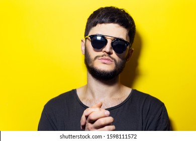 Studio Portrait Of Serious Confident Man With Sunglasses On Yellow Background.