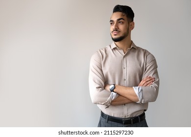 Studio Portrait Of Serious Indian Man Looking Aside Standing Over Grey Copy Space Background. Young Adult Hindu Male Entrepreneur, Leader Or Successful Freelance Worker Showing Confidence Expression