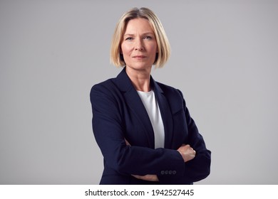 Studio Portrait Of Serious Mature Businesswoman Against Plain Background