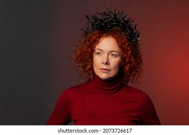 Studio Portrait Of A Serious Woman 35-40 Years Old With A Crown On Her Head In The Form Of Snakes On A Colored Background.