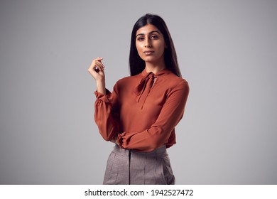 Studio Portrait Of Serious Young Businesswoman Against Plain Background