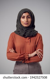 Studio Portrait Of Serious Young Businesswoman With Folded Arms Wearing Headscarf Against Plain Background