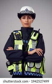 Studio Portrait Of Serious Young Female Police Officer Against Plain Background