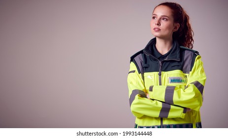 Studio Portrait Of Serious Young Female Paramedic Against Plain Background