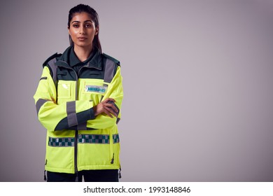 Studio Portrait Of Serious Young Female Paramedic Against Plain Background