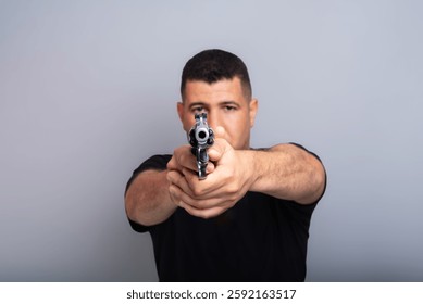 Studio portrait of a shooting instructor pointing a firearm at the camera. Brazil