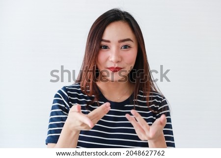Studio portrait shot of Asian young female model in casual clothing  poses to cameran in positive friendly action  on white background.