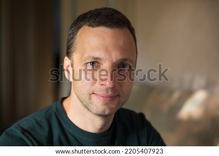 Studio portrait of slightly smiling young adult Caucasian man, selective focus