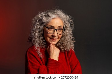 Studio Portrait Of A Smiling Elderly Woman 60-65 Years Old With Glasses, With Gray Curly Long Hair, On A Colored Background, Concept: Stylish Pensioners And Grandmothers Of Model Appearance.