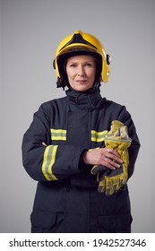 Studio Portrait Of Smiling Mature Female Firefighter Against Plain Background