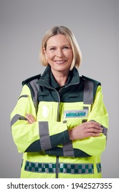 Studio Portrait Of Smiling Mature Female Paramedic Against Plain Background