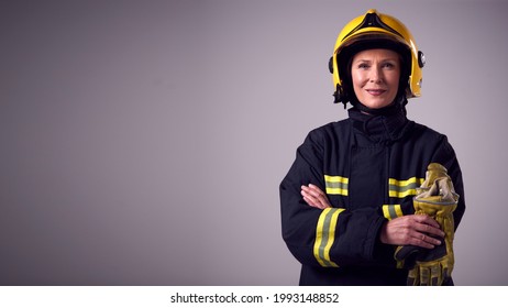 Studio Portrait Of Smiling Mature Female Firefighter Against Plain Background