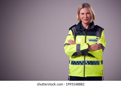 Studio Portrait Of Smiling Mature Female Paramedic Against Plain Background