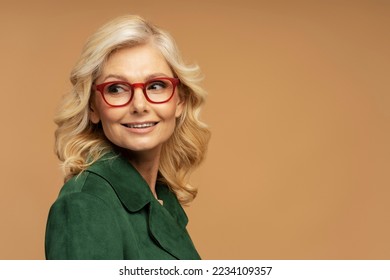 Studio portrait of smiling mature woman wearing red stylish eyeglasses looking away isolated on background, copy space. Advertisement concept 