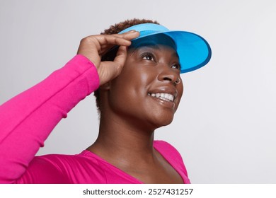 Studio portrait of smiling woman wearing blue sun visor and pink shirt - Powered by Shutterstock