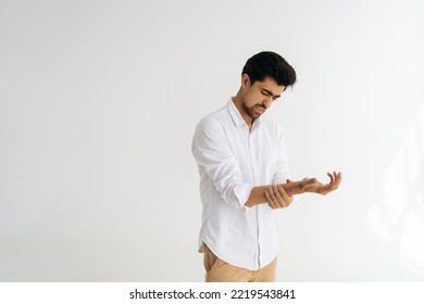 Studio Portrait Of Unhappy Frustrated Bearded Young Man Massaging Painful Wrist, Suffering Hand Sprain Or Arthritis Inflammation, Carpal Tunnel Syndrome Standing On White Isolated Background