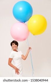 Studio portrait of woman with bunch of colorful balloons against plain background