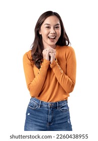 A studio portrait of a young Asian Indonesian woman wearing an orange long-sleeve shirt looks happy as she smiles while her hands are clasped in front of her chest. Isolated on a white background.