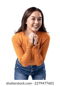 A studio portrait of a young Asian Indonesian woman wearing an orange long-sleeve shirt looks happy as she smiles while her hands are clasped in front of her chest. Isolated on a white background. - Shutterstock ID 2279477601