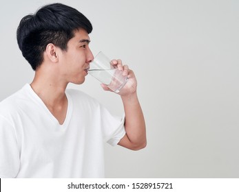 Studio Portrait Of Young Asian Man Drinking Water On White Background.