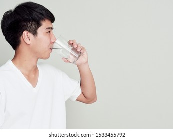 Studio Portrait Of Young Asian Man Drinking Water On White Background.