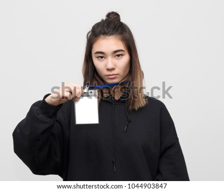 Studio portrait of young attractive woman holding blank artist lanyard or badge in hand with metal piece. Plastic pass concept