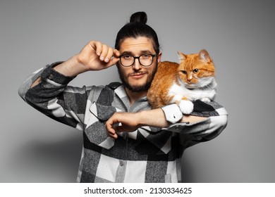 Studio portrait of young confident man with red cat on his arm.