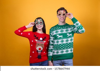 Studio Portrait Of Young Couple, Boyfriend & Girlfriend Wearing Ugly Christmas Sweater. Holiday Outfit W/ Snowflake Pattern Print. Close Up, Copy Space For Text, Isolated Background.