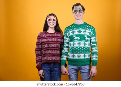 Studio Portrait Of Young Couple, Boyfriend & Girlfriend Wearing Ugly Christmas Sweater. Holiday Outfit W/ Snowflake Pattern Print. Close Up, Copy Space For Text, Isolated Background.