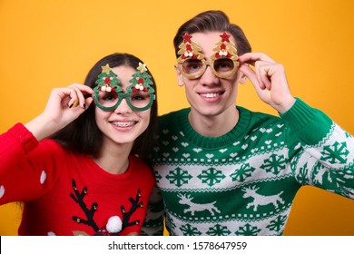 Studio Portrait Of Young Couple, Boyfriend & Girlfriend Wearing Ugly Christmas Sweater. Holiday Outfit W/ Snowflake Pattern Print. Close Up, Copy Space For Text, Isolated Background.